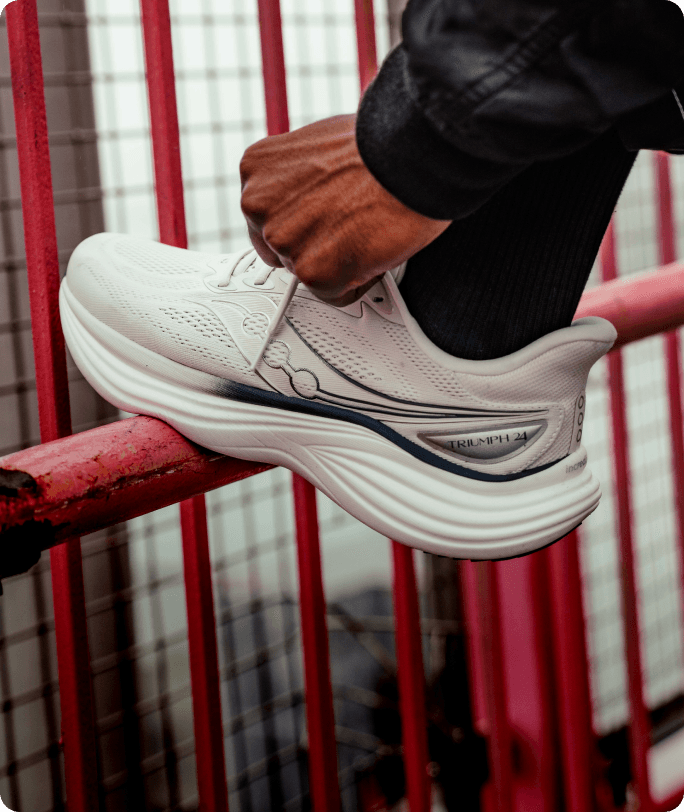 Gros plan sur les pieds d'une personne portant des chaussures Saucony Triumph 24, debout sur un trottoir avant une course.