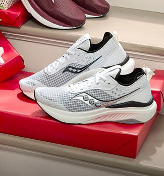 A pair of white and black Saucony sneakers on a red box.