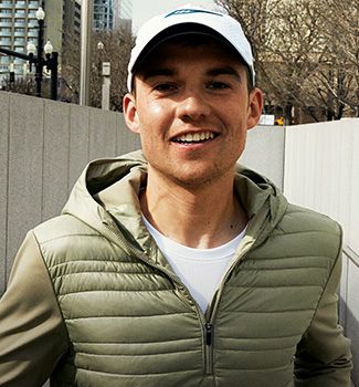 A person wearing a white Saucony hat and a green jacket.