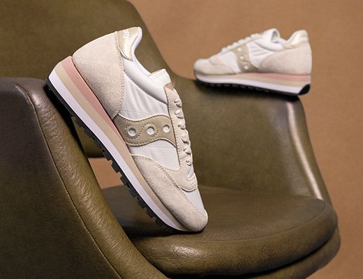 A pair of white and pink Saucony lifestyle shoes on a chair.
