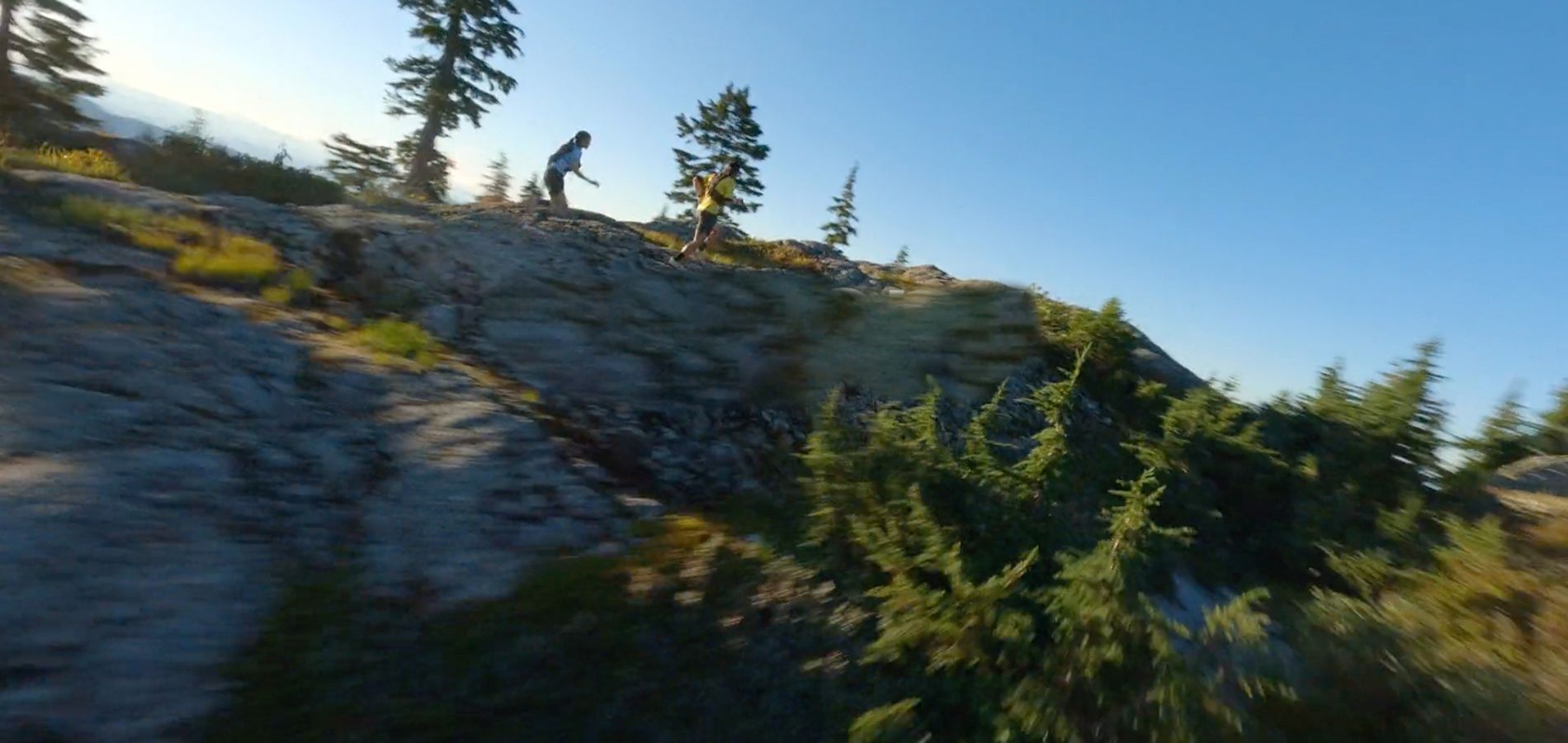 Two people running on a rocky hill.