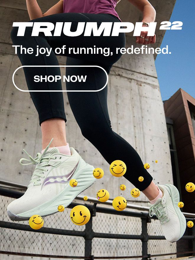 A person's legs in black pants and white Triumph 22 shoes.