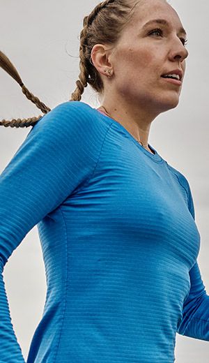 A person with braided hair and a blue Saucony shirt.