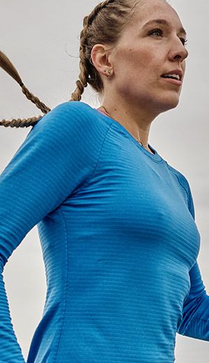 Une personne avec des cheveux tressés et un t-shirt bleu de Saucony.