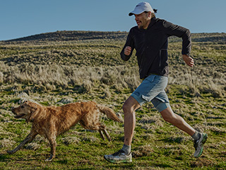 Une personne courant avec un chien sur un sentier, portant des chaussures Saucony.