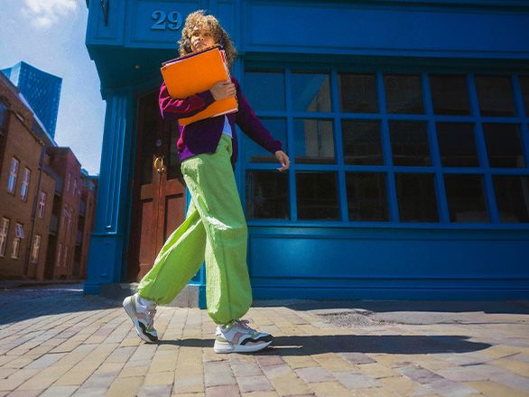 A person walking on a brick sidewalk holding files.