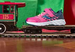 Une chaussure rose et bleue Saucony sur un train-jouet.