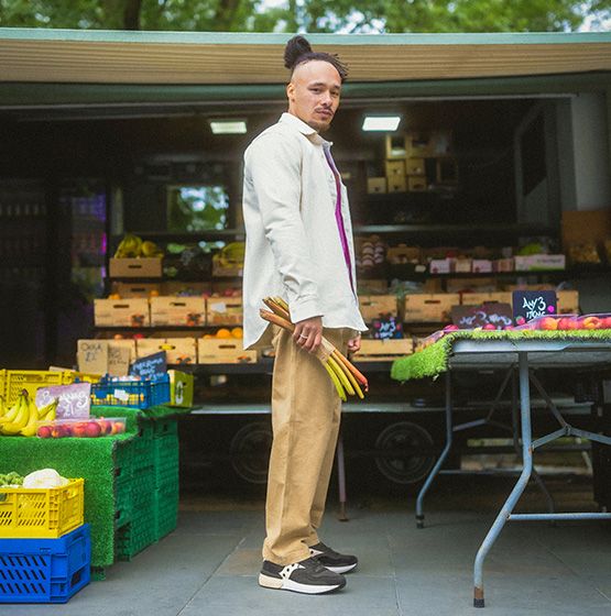 A man standing in front of a fruit stand wearing Jazz NXT shoes.