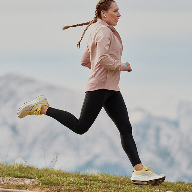 A person running on a trail wearing Saucony shoes.