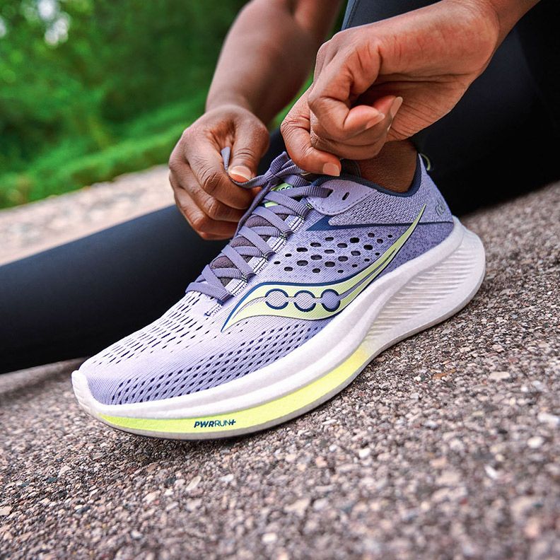 A person tying a shoelace on Saucony Ride 17 shoe.