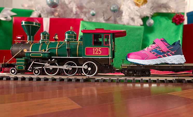 A toy train with a kids' Saucony pink shoe on it.