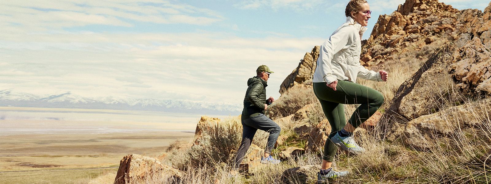 A group of people running on a rocky hill wearing Saucony gear.