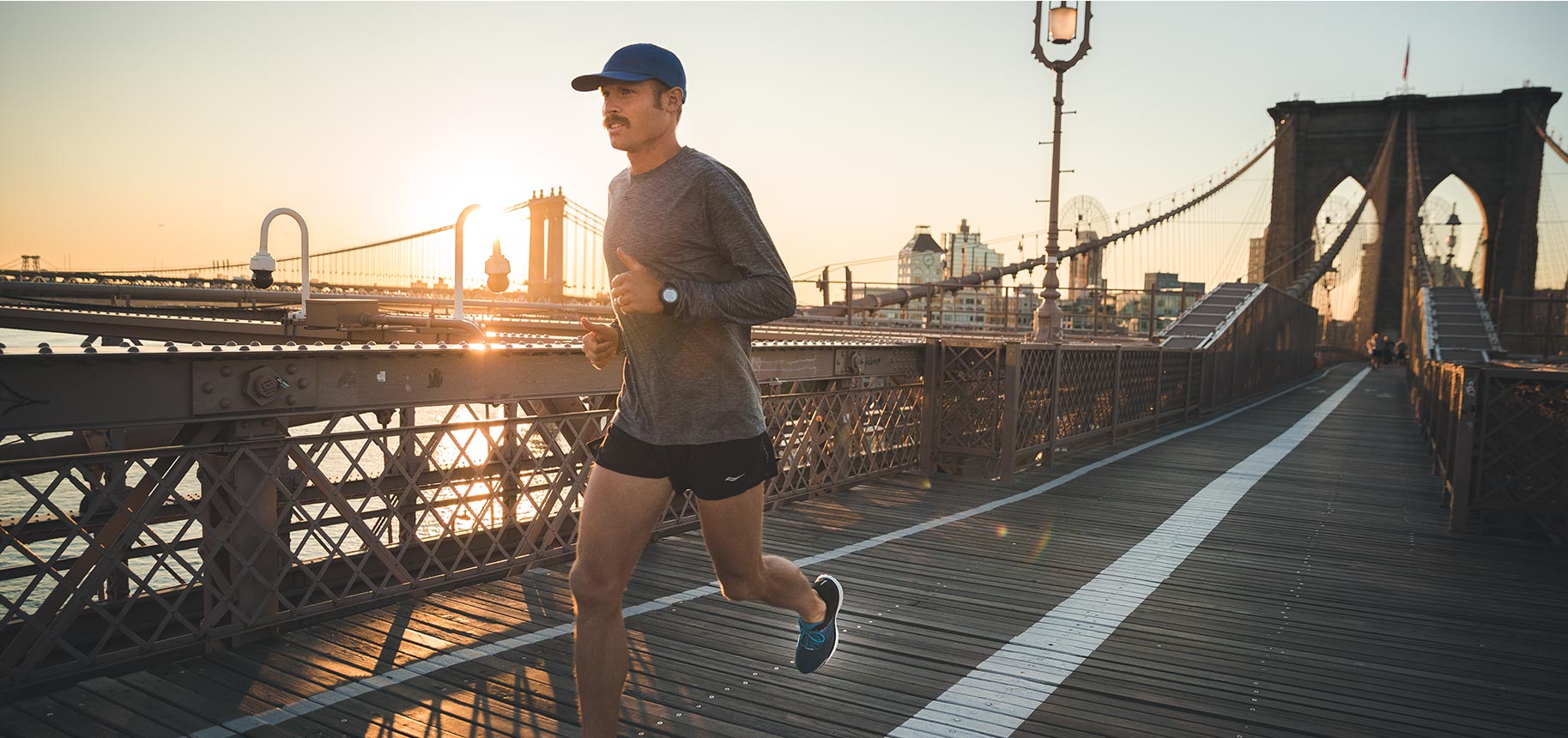 Jared Ward running on a bridge with the city skyline in the background.