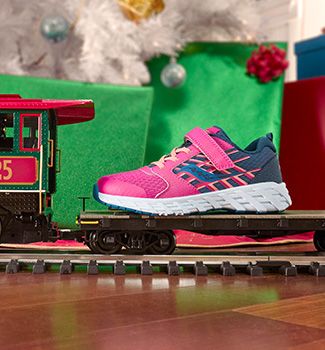 Une chaussure Saucony rose et bleue sur un train-jouet.