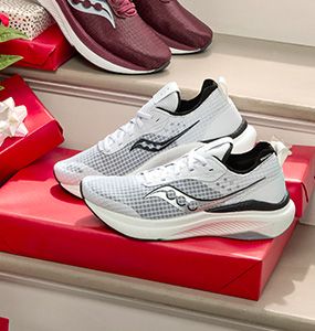 A pair of white and black Saucony sneakers on a red box.