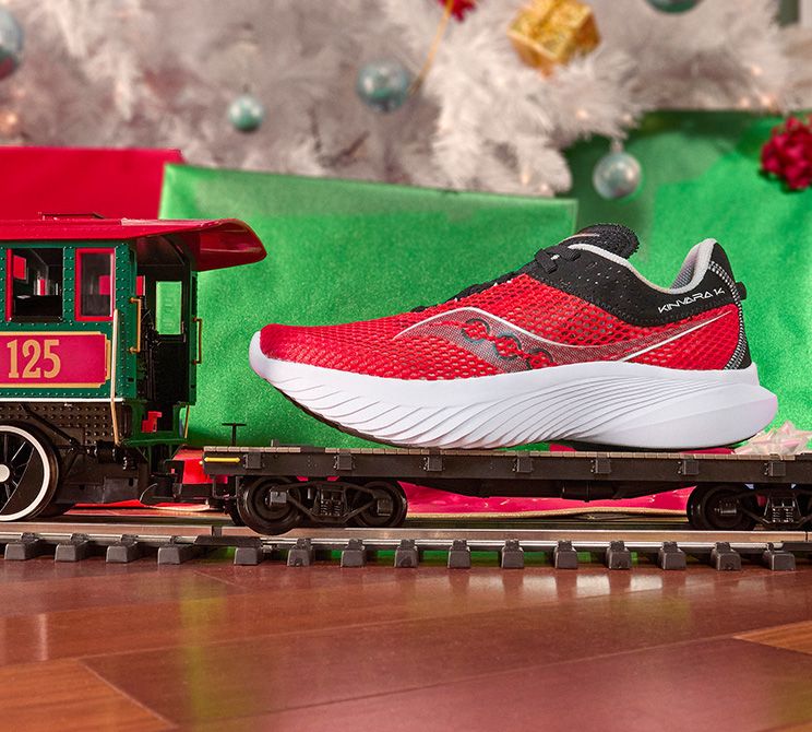 Un train-jouet avec une chaussure de course Saucony Kinvara 14 posée dessus.