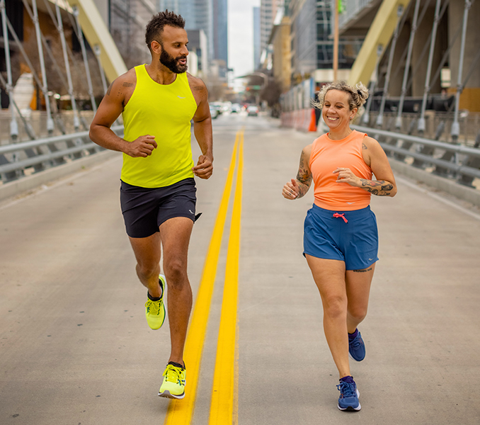 Two runners cross a bridge in the middle of the road.