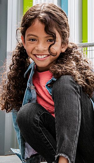 A child with curly hair smiling.