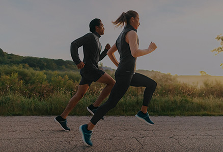 A male and female running into the sunset.