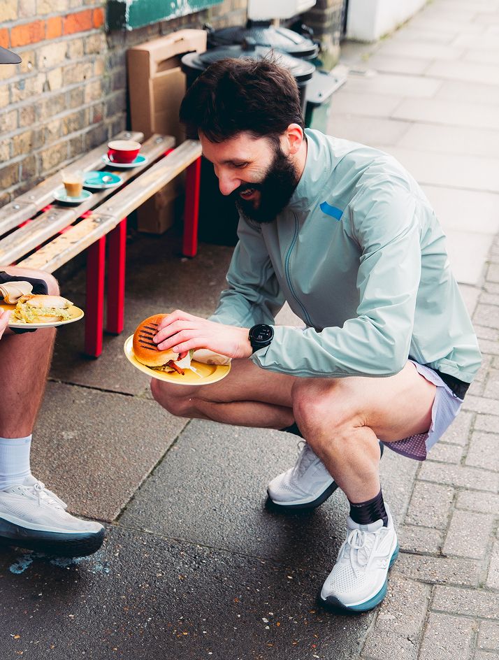 a man squatting down holding a burger
