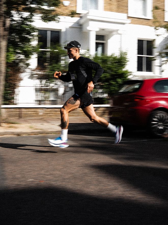 Runner wearing performance trainers jogging along a residential street.