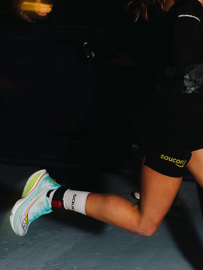 Close-up of a runner's lower body wearing Saucony Endorphin Azura running shoes on an indoor track.