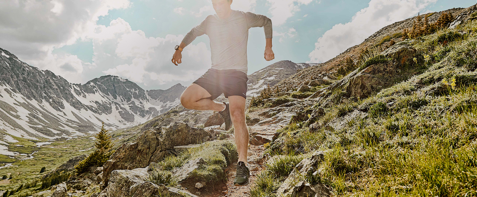 A man wearing Xodus ISO 3's in mid-air, jumping over a rocky terrain.