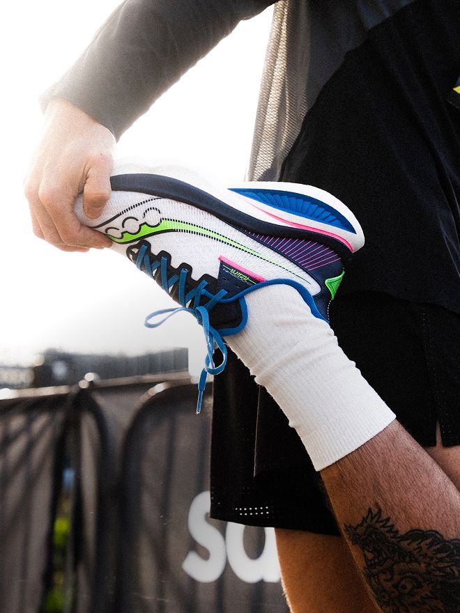 Close-up of a runner adjusting a white and blue athletic shoe before a workout
