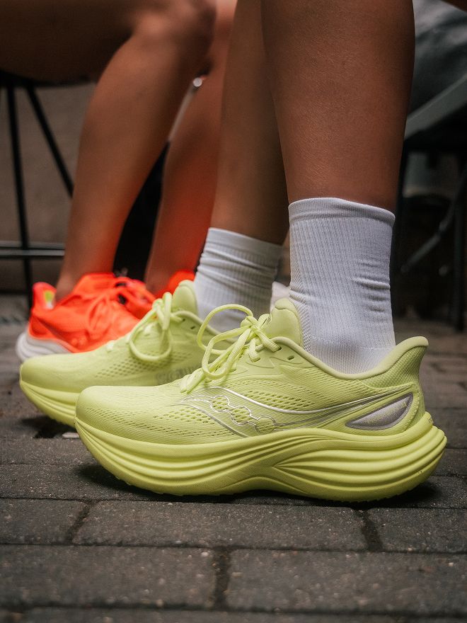 Des personnes portant des Saucony Triumph 24 discutent ensemble avant une course.