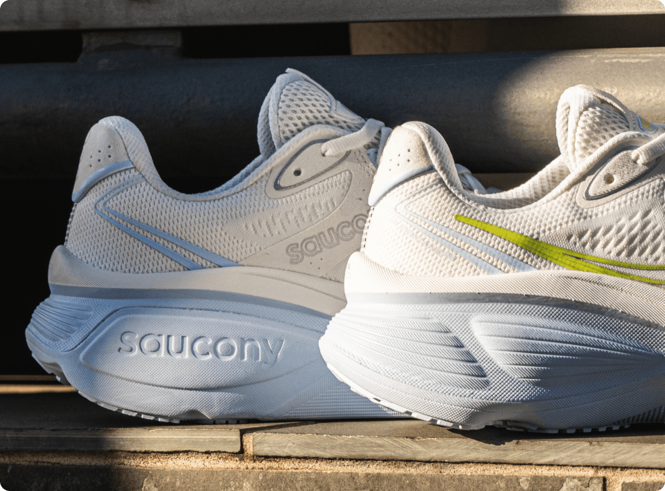 A pair of white and blue Saucony running shoes resting on a ledge in the sunlight.