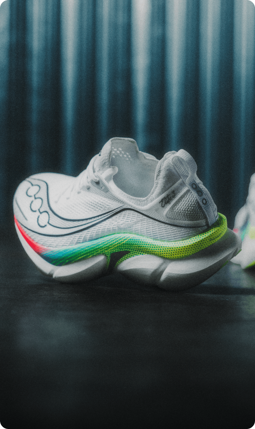 A pair of white Saucony running shoes with a rainbow gradient outsole.