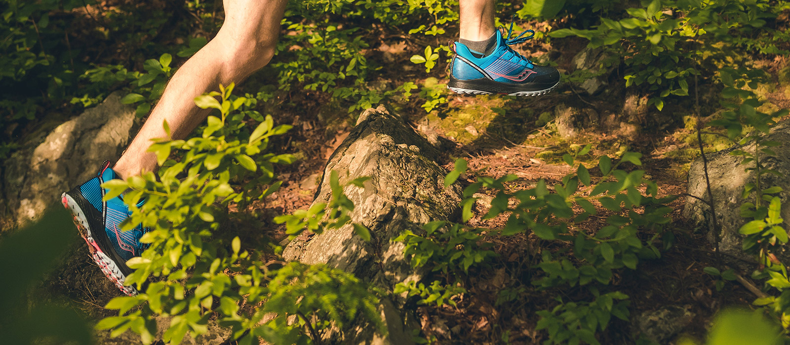 Mens feet running thru the woods with blue Mad River TR shoes on.