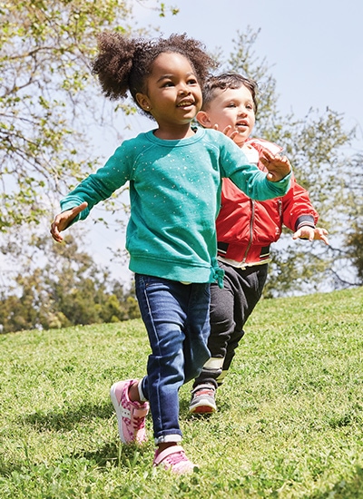 Two little kids running in the grass