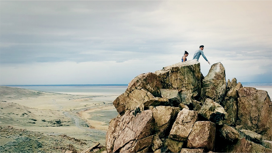 Video poster for Xodus ISO 3 promo video. Two people hiking on a rocky terrain.