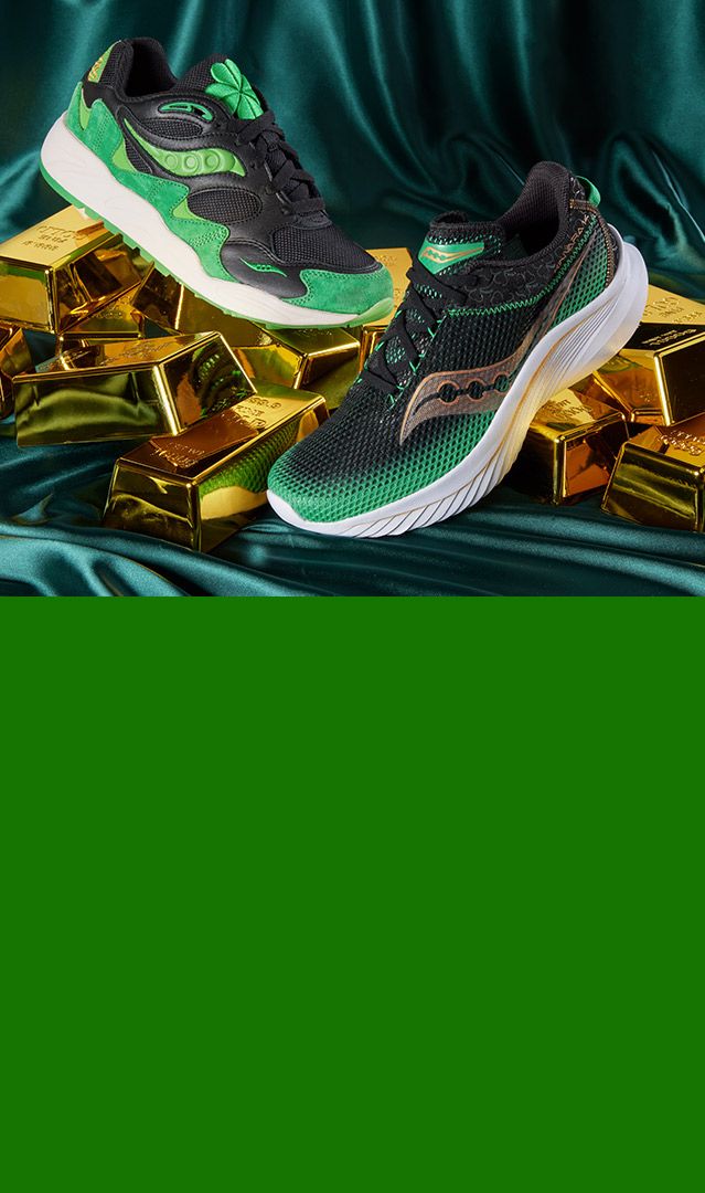 Green and black Saucony shoes on gold bars.