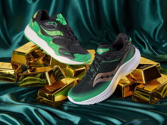 Green and black Saucony shoes on gold bars.
