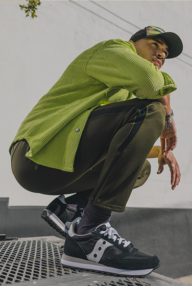 Crouching while wearing blue, silver and pink Jazz sneakers.