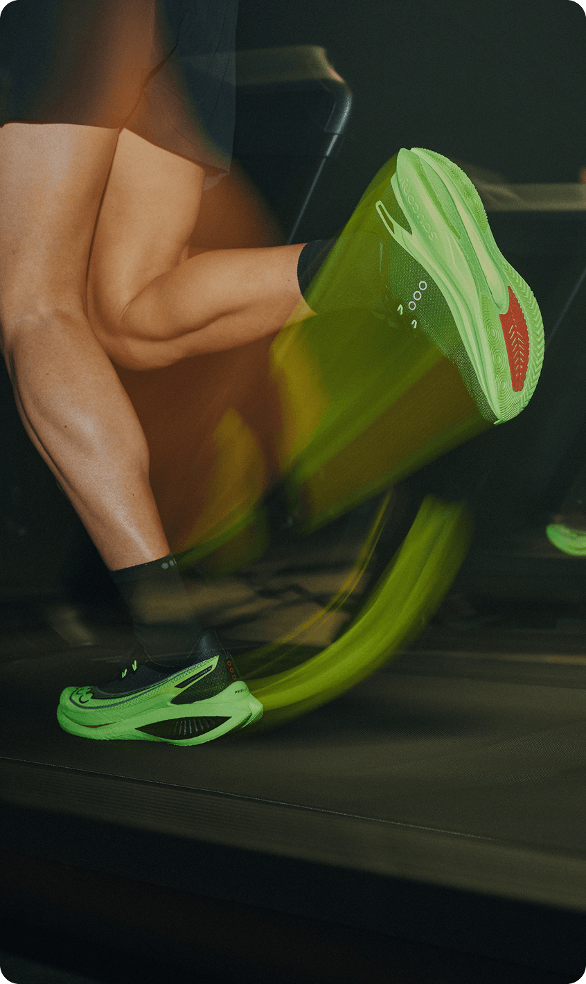 Runners wearing bright green Saucony running shoes on treadmills.
