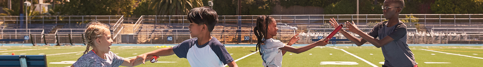 Kids exchanging a relay baton on a running track.
