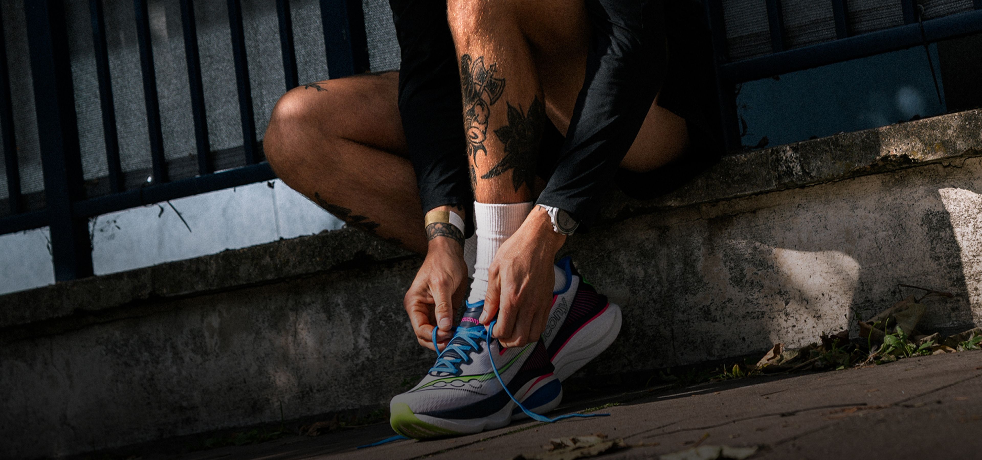 A person lacing up Saucony running shoes.