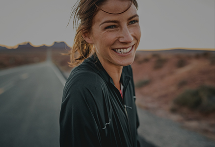 Female smiling with background out of focus of a desert road.