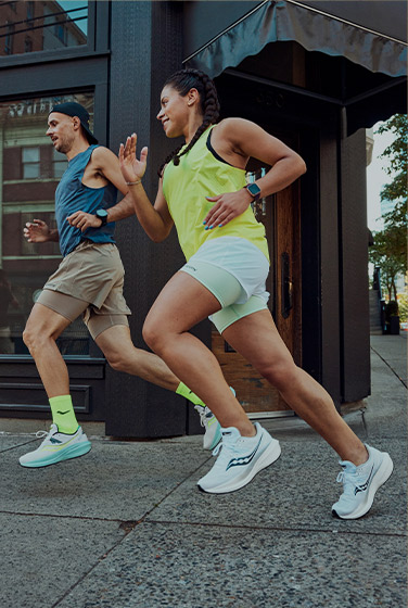 Two runners rounding a corner in a city wearing Triumph 20s.