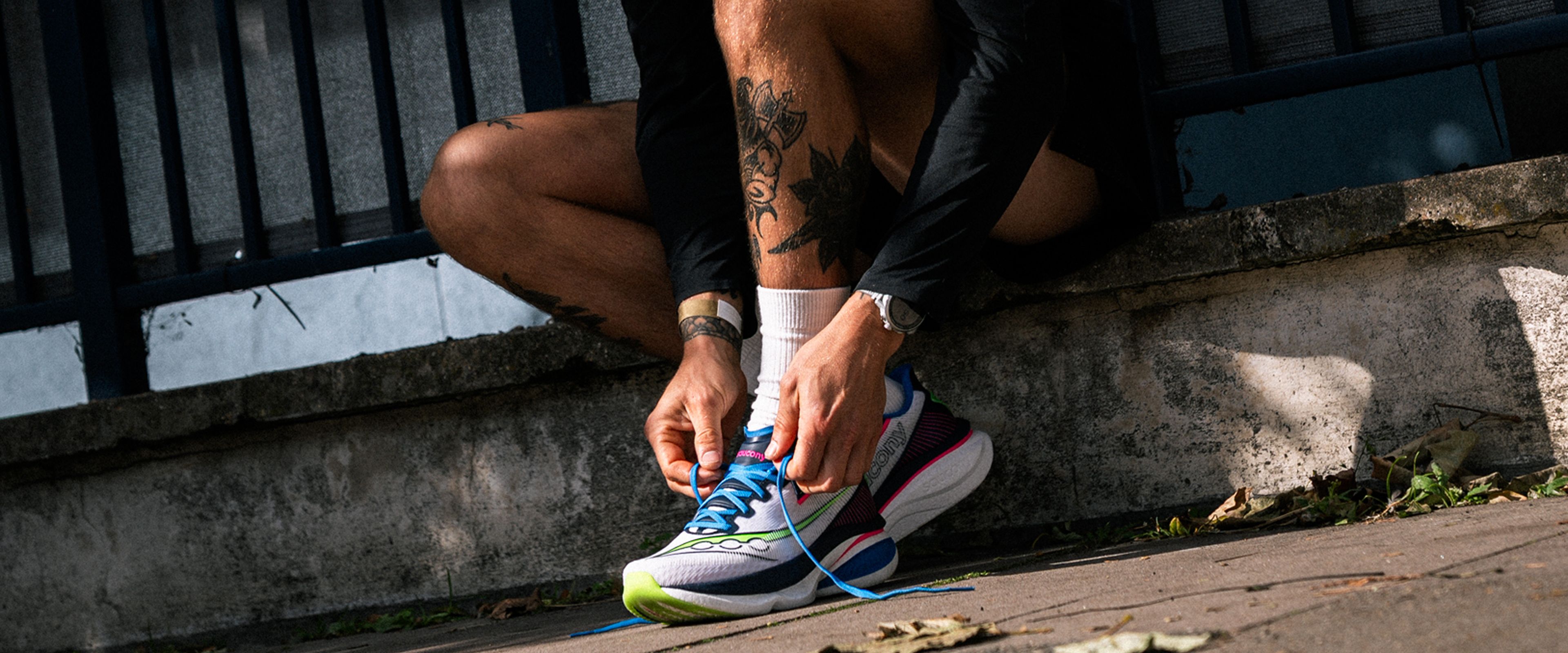A person tying their Saucony shoes.