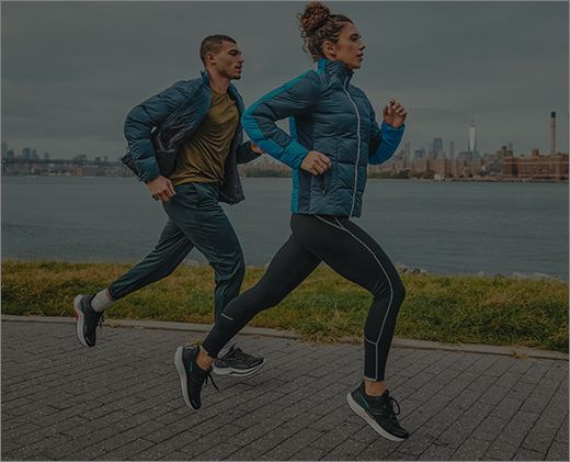 A man and woman running outside in Saucony runnng shoes.