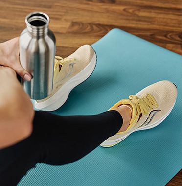 a person holding a bottle of water on a mat