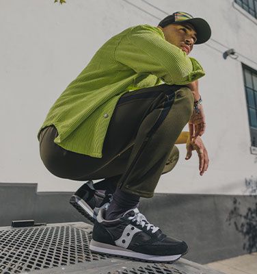 Crouching while wearing blue, silver and pink Jazz sneakers.