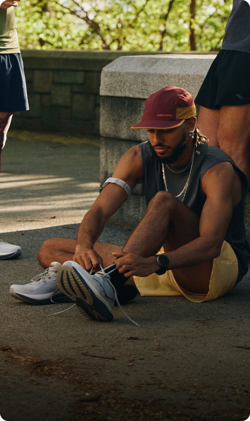 A person lacing up their Saucony shoes.