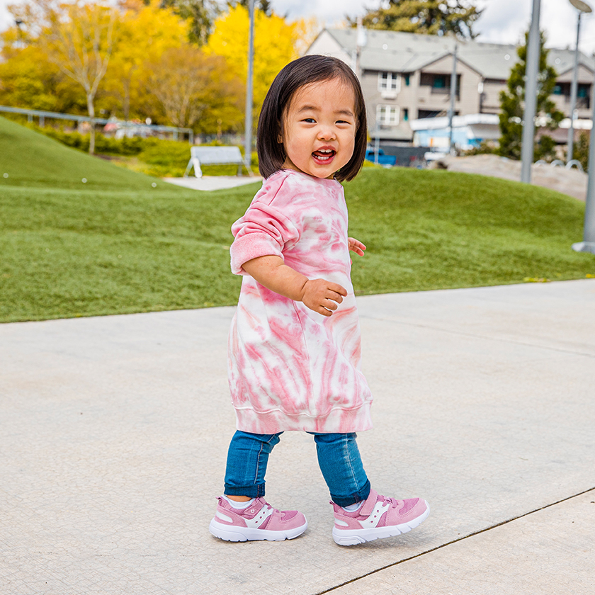 A kid walking down the sidewalk with an outfit that matches their shoes  .