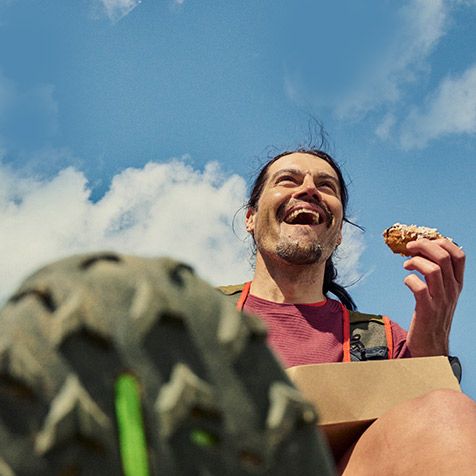 A person enjoying a donut on a sunny day.