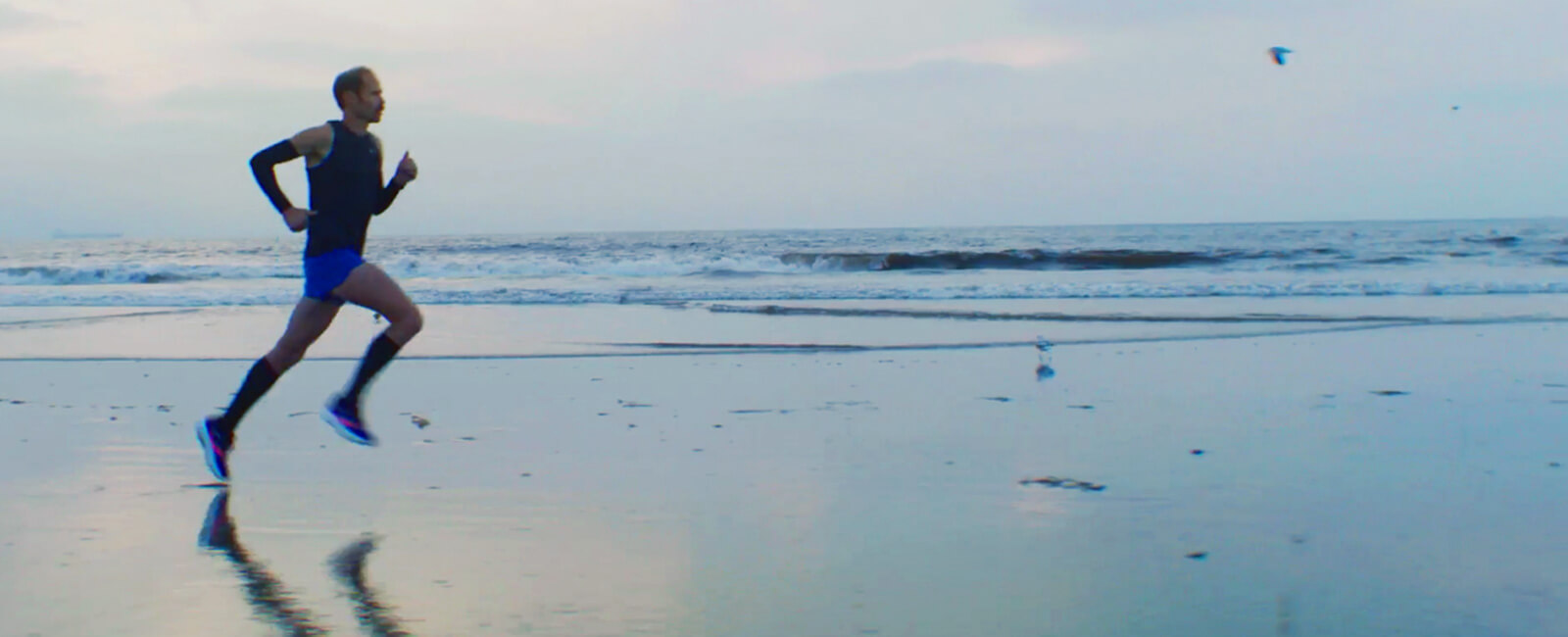 Person wearing Saucony running shoes jogging on the beach.